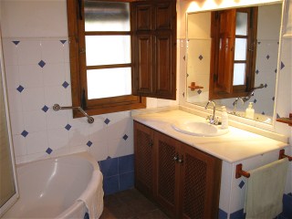 Das zweite Bad hat eine Eckbadewanne mit Duschwand und einen Marmor-Waschtisch mit grosser Spiegelwand.